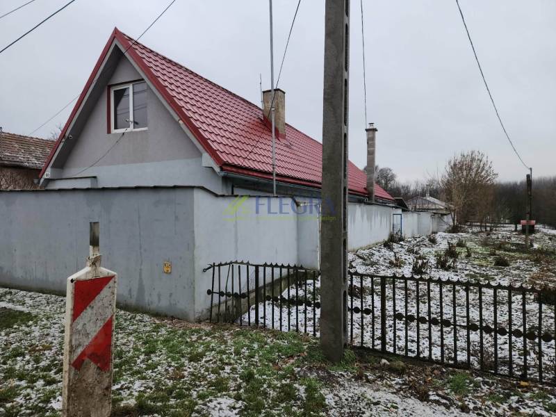 A family house in Tornyosnémeti with a red roof, a side fence, and a snow-covered garden.