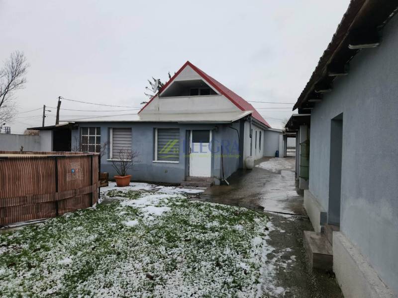 The snowy yard of a family house in Tornyosnémeti with a garden pool and a concrete walkway.