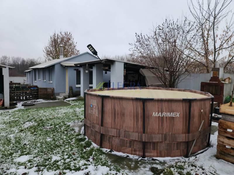 A snowy yard of a family house in Tornyosnémeti with a swimming pool and a wooden gazebo.