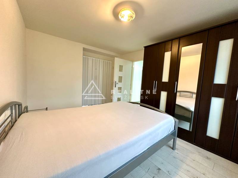 Bedroom in a two-room apartment with a bed, wardrobe, and floor with a wooden decor.