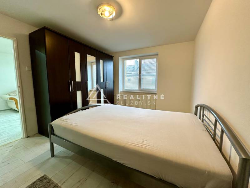 Bedroom with a large wardrobe and bed in a 2-room apartment, light floor with wood decor.