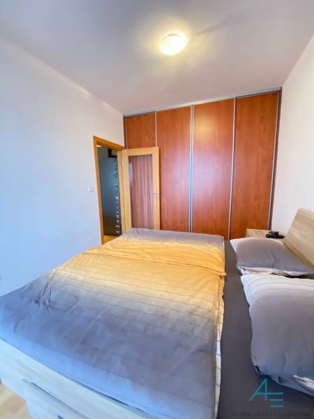 A bedroom in a two-room apartment with a built-in wardrobe and a bed with a wooden decor.