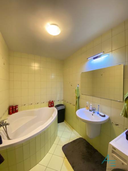 Bathroom in a 2-room apartment with a bathtub, sink, and mirror on the wall.