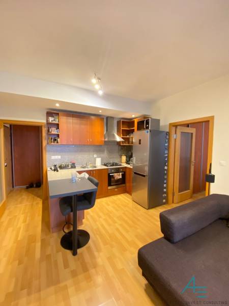A kitchen in a 2-room apartment with a wooden decor floor and a bar counter.