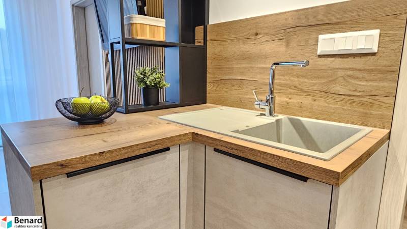 Kitchen unit in a one-room apartment with a sink and a wooden decor floor.