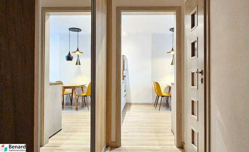 A lit dining room with a kitchen table and yellow chairs in a studio apartment.