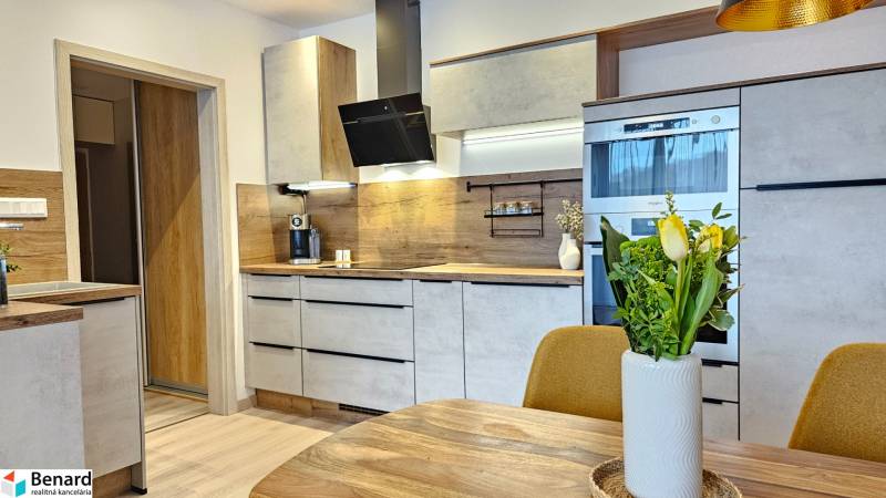 A kitchen in a studio apartment with wooden floor decor and modern equipment.