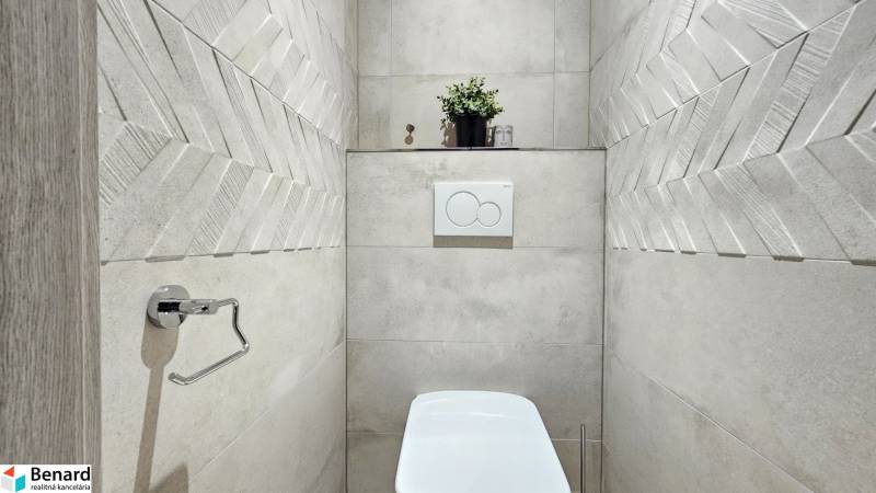 Bathroom in a studio apartment with modern tiles and a decorative plant.