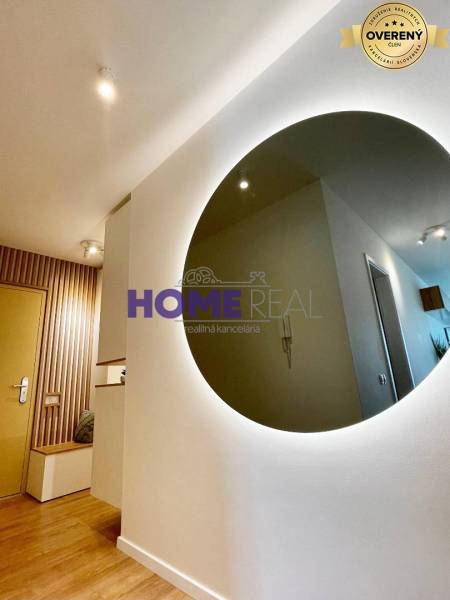 Interior of a 3-room apartment with a wooden decor floor and a round mirror on the wall.