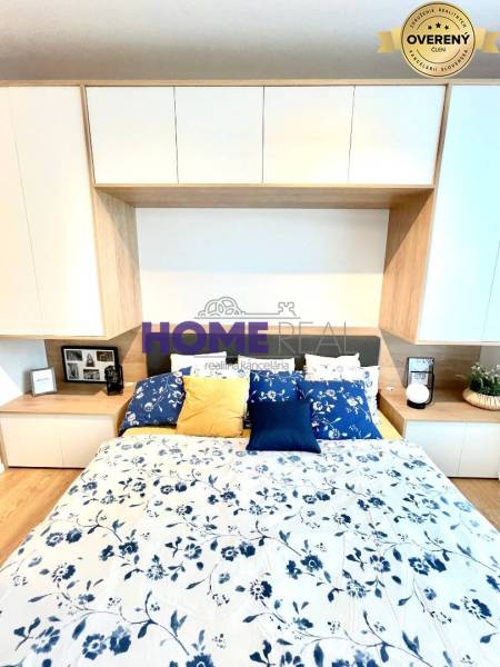 Bedroom in a 3-room apartment with a wooden decor floor and floral bedding.