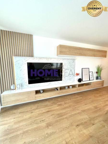 Living room wall unit with a television and a floor with a wooden decor in a 3-room apartment.