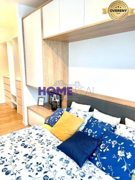 Bedroom in a 3-room apartment with a bed, colorful pillows, and storage spaces.