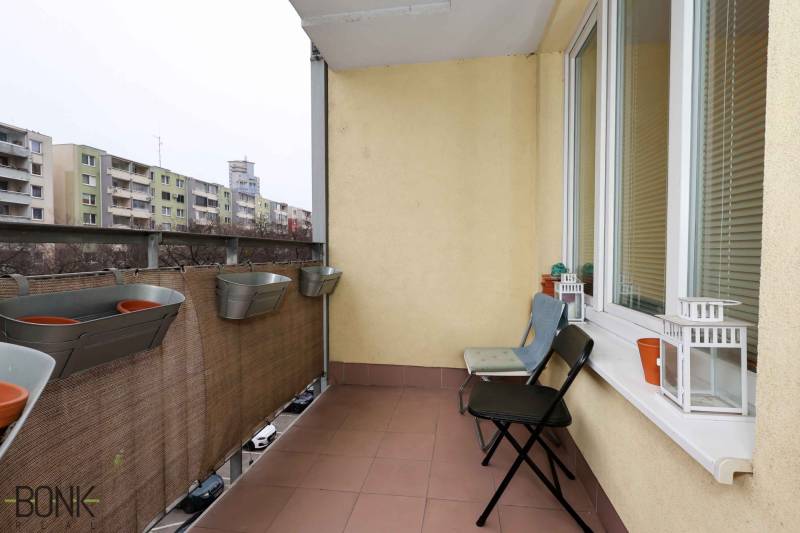 The balcony of a 2-room apartment at Jégeho 8 in Bratislava-Ružinov with flower pots and chairs.
