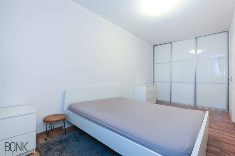 Bedroom in a 2-room apartment with a large built-in wardrobe and a floor with a wood decor.