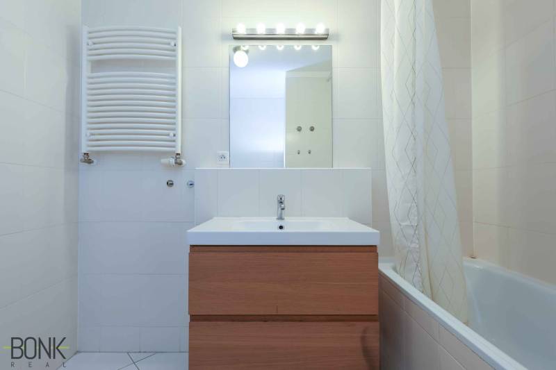 Bathroom in a 2-room apartment with a sink, mirror, and bathtub.