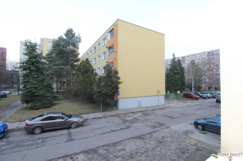 Apartment building in Bratislava on Cabanova Street in an environment with coniferous trees.