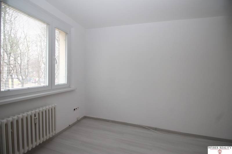 A room with white walls and a wooden decor floor in a 3-room apartment.