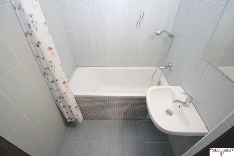Bathroom with a bathtub and a sink in a 3-room apartment with tiles.