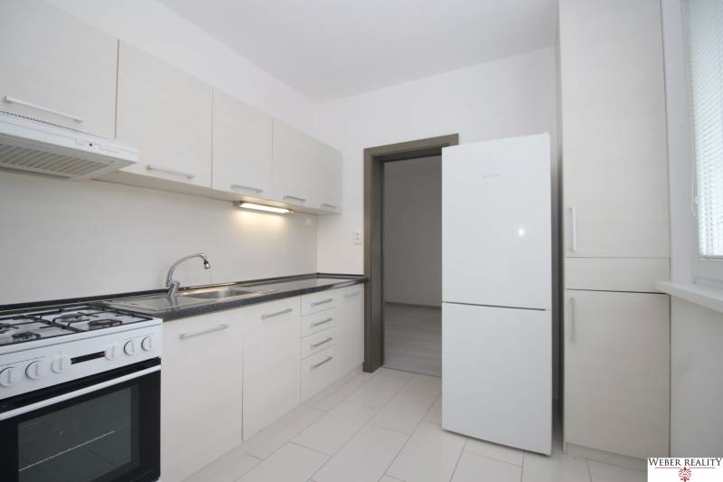 A kitchen in a 3-room apartment with white cabinets and a white floor.