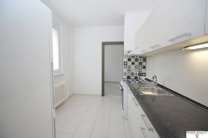 A kitchen in a 3-room apartment with tiled flooring, patterned tiles near the stove.