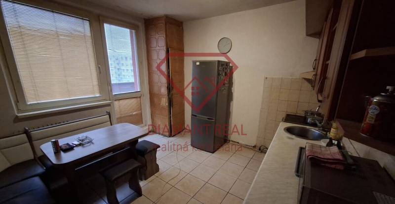 Kitchen in a 3-room apartment with a dining table and a refrigerator, tiled floor.