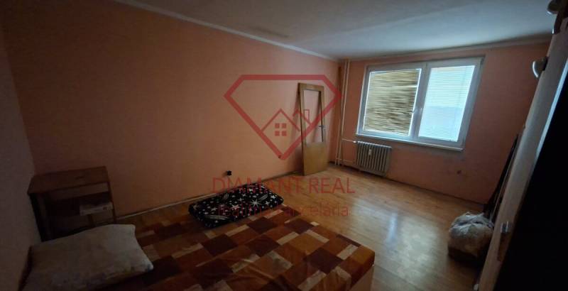 A room in a 3-room apartment with a wooden decor floor, simple furnishings.