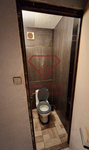 A toilet with tiles in a 3-room apartment, dark tiles on the walls.