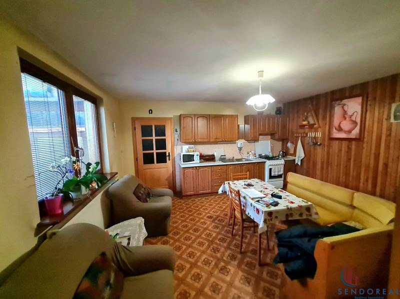 A kitchen in a family house with wooden decor, a sofa set, and a dining table.