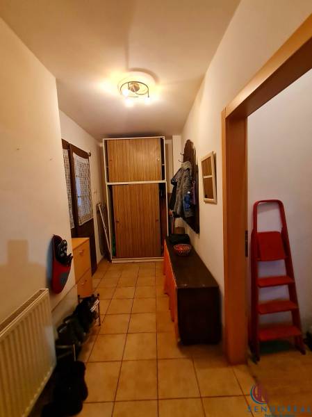 A hallway in a family house with tiles, a shoe cabinet, a coat rack, and a wardrobe.