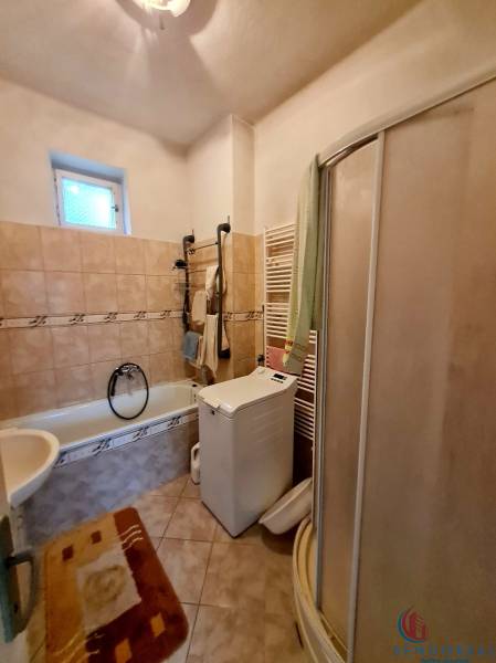 Bathroom with a bathtub, shower, and washing machine in a family house.