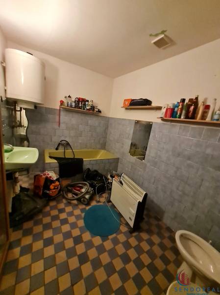 Bathroom in a family house with a bathtub, sink, shelves, and a heating unit.