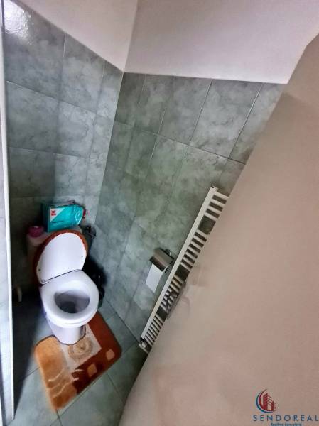 A bathroom with a toilet in a family house, tiled with light green tiles.