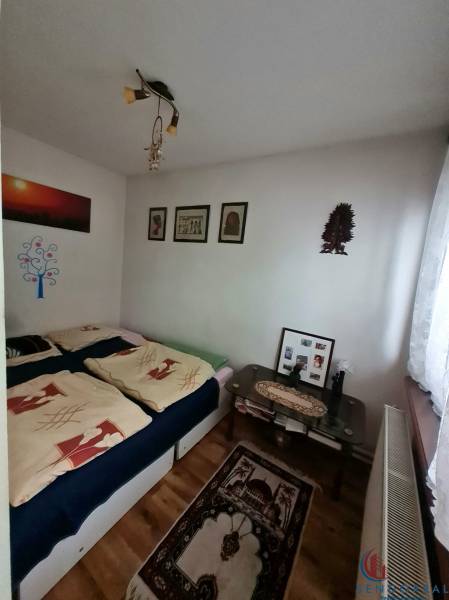 A bedroom in a family house with a wooden decor floor, pictures, and decorative items.