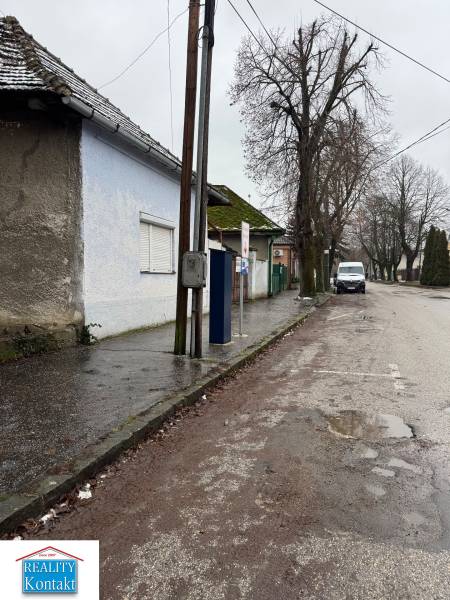 A family house on Komenského Street in Šurany, by the road with an electric pole and trees.