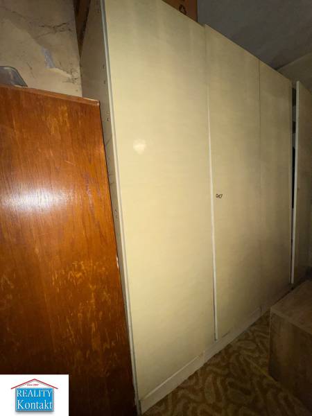 A wardrobe in a family house, next to it is brown furniture and a carpet with a geometric pattern.