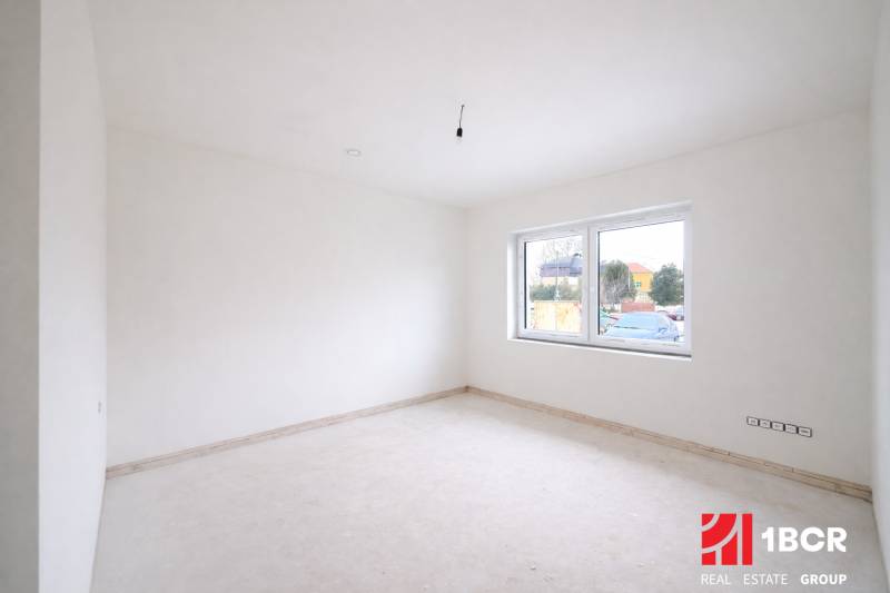 An empty room with white walls and a large window in a family house.