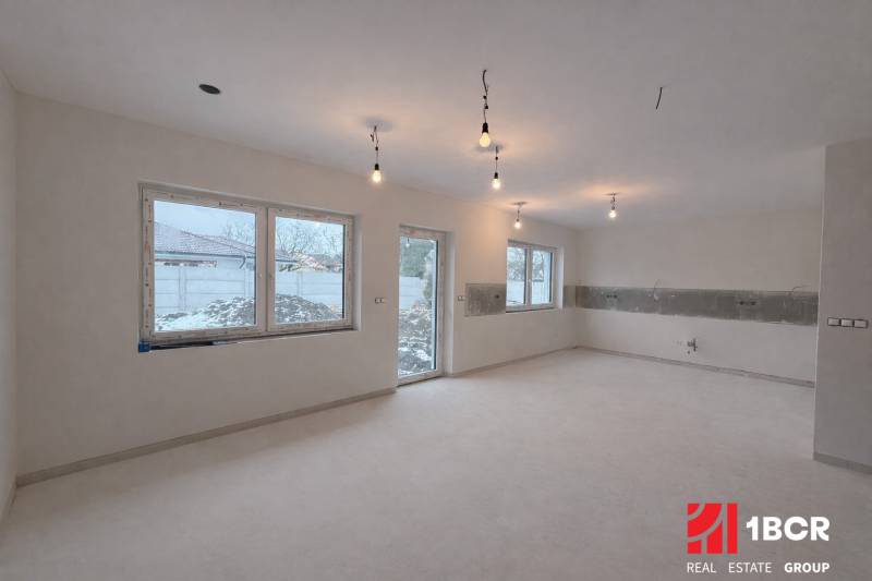 Interior in a family house with light flooring and large windows, without furniture.