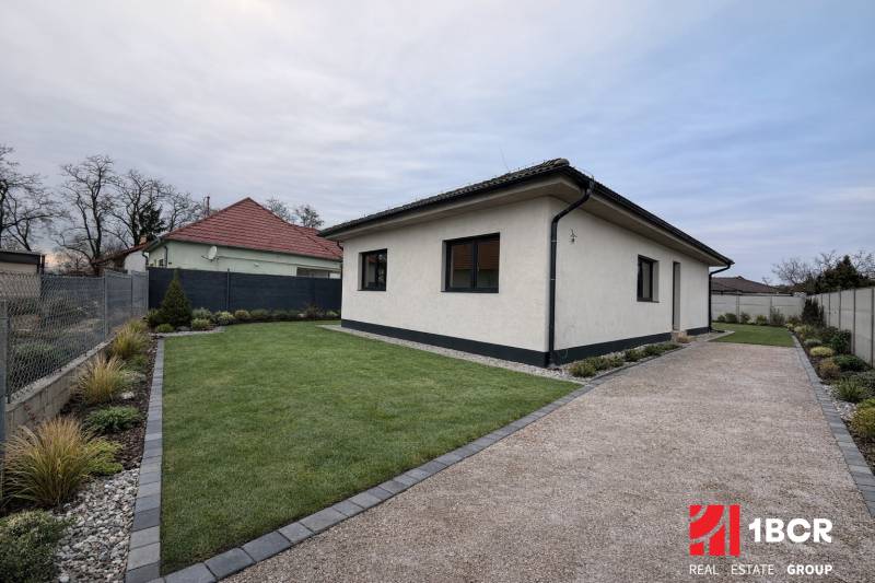 A family house in Veľký Grob with a lawn, gravel path, and landscaped garden.