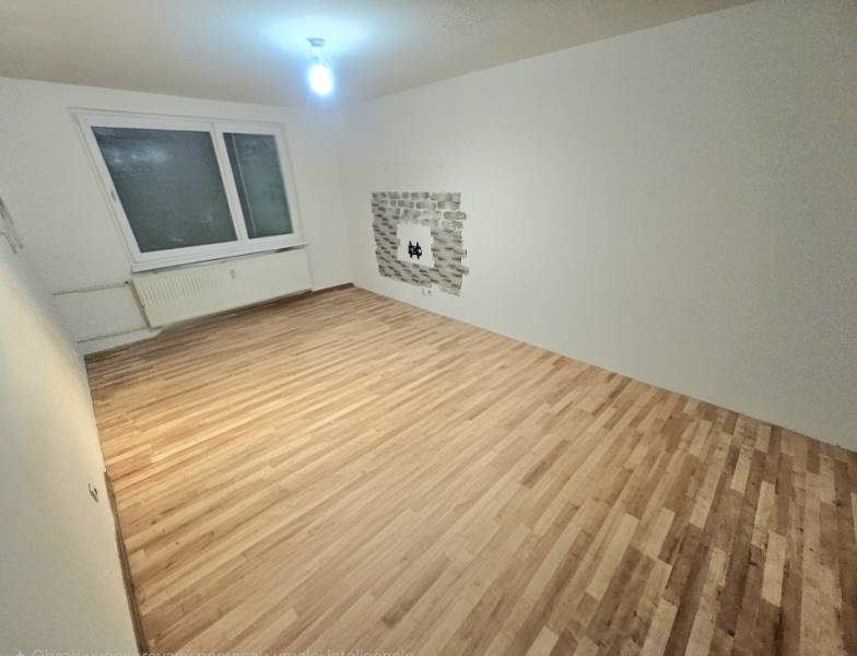Living room with wood-patterned flooring and a window in a 3-room apartment.
