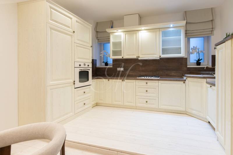 The kitchen in a 3-room apartment with a cream kitchen unit and a white floor with a wooden decor.
