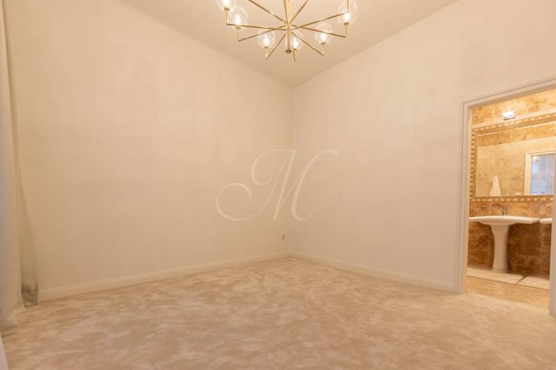 The interior of a bright room in a 3-room apartment with a soft carpet and a sheer curtain.