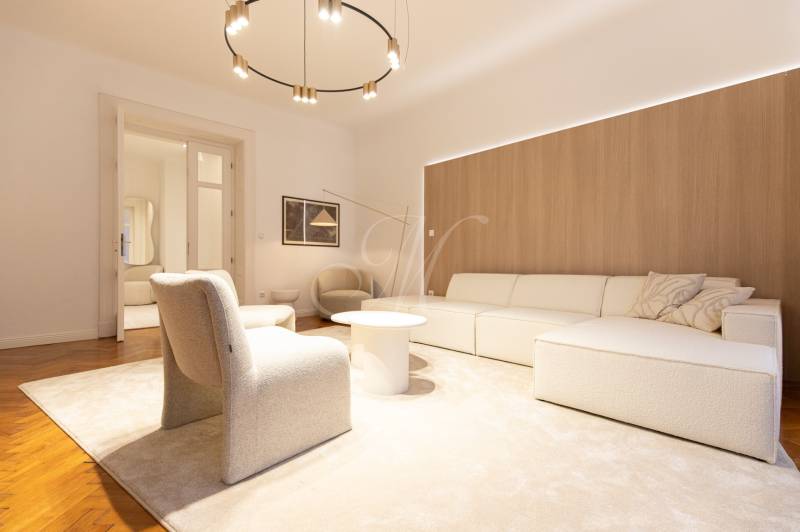 Living room in a 3-room apartment with a sofa, armchair, carpet, and wooden decor flooring.