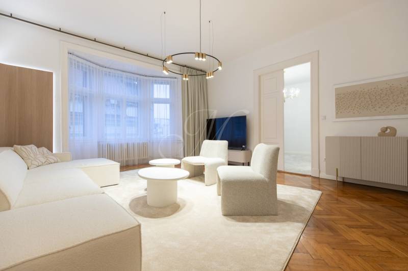 Living room with wood-patterned flooring, sofa, tables in a three-room apartment.