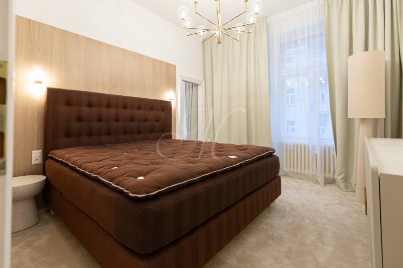 A bedroom in a 3-room apartment with curtains, an upholstered bed, and a pendant light.