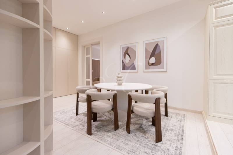 Dining area in a 3-room apartment with a round table and chairs on a wood-patterned floor.