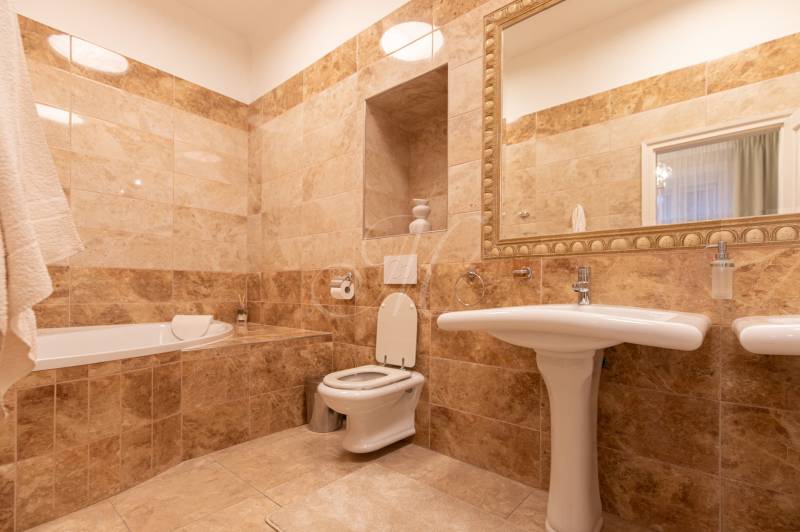 Bathroom with a mirror, sink, and bathtub. Tiles in earthy tones complement the interior decoration.