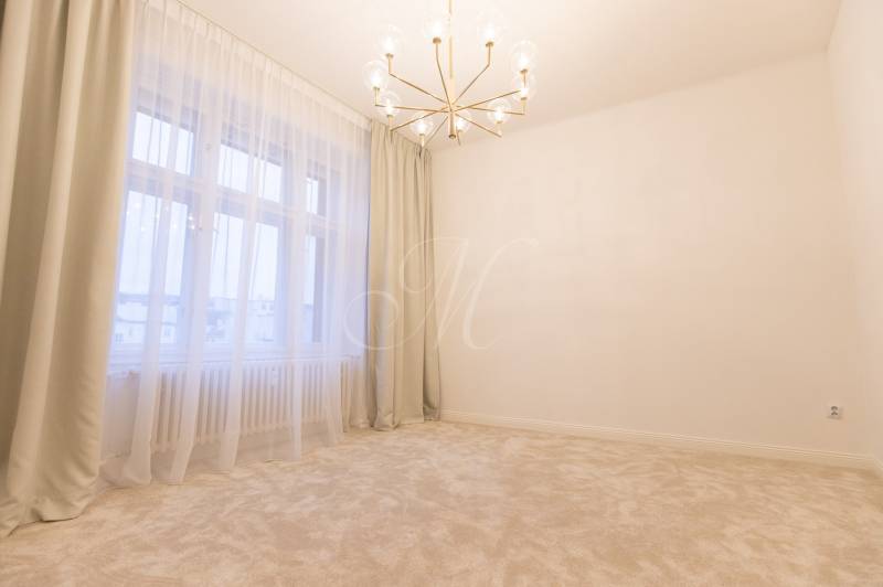 A room in a 3-room apartment with a chandelier, curtains, and a light carpet.