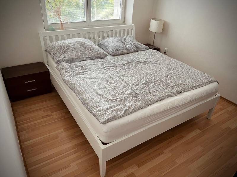 Bedroom in a two-room apartment with a wood-decor floor and a double bed.