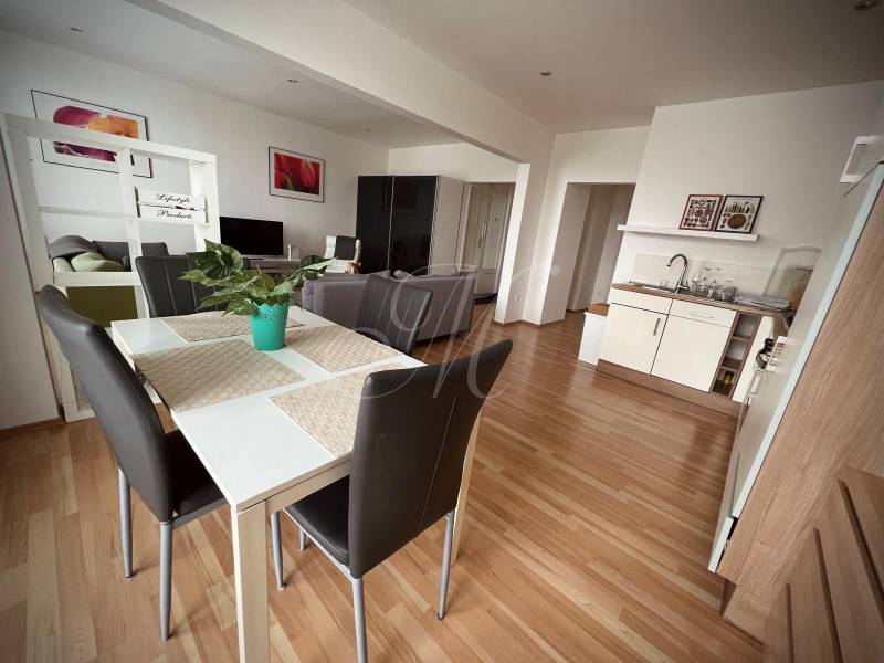 Interior of a 2-room apartment with a kitchen, dining table, and floor with wooden decor.