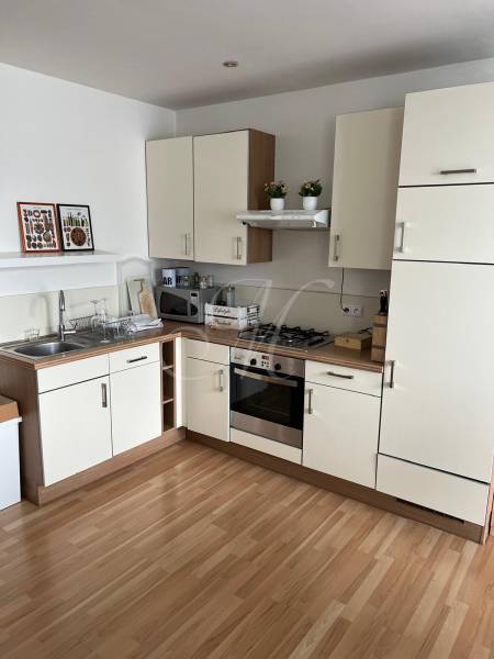 Kitchen in a 2-room apartment with wooden floor decor, kitchen cabinets, stove, and accessories.